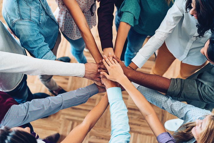 Group of people with one hand in middle in-focus.